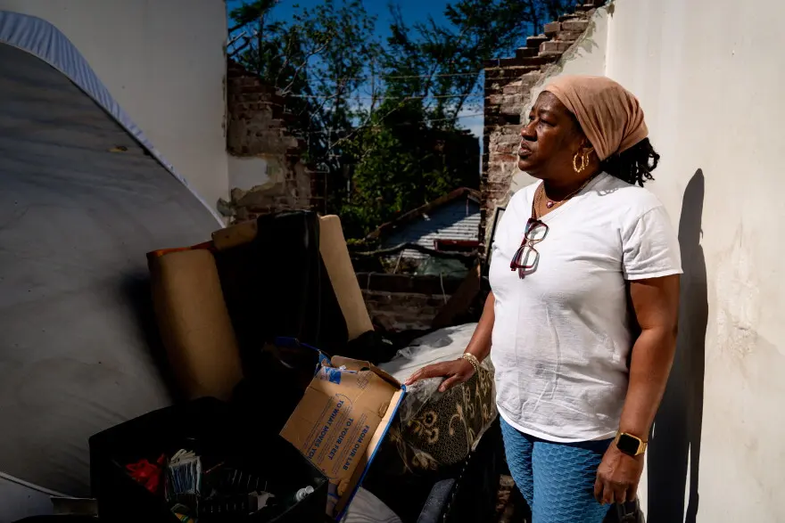 Dolly Baskin stands where her bedroom used to be at her north St. Louis home on Saturday, May 17, 2025. A storm on Friday blew the roof off and ripped off the back of her home.