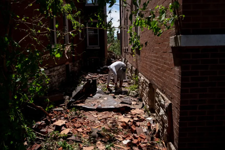 Marco Turner picks up bricks and debris after a tornado ripped through north St. Louis the evening before on Saturday, May 17, 2025. At least 5 were killed and thousands of homes were damaged.