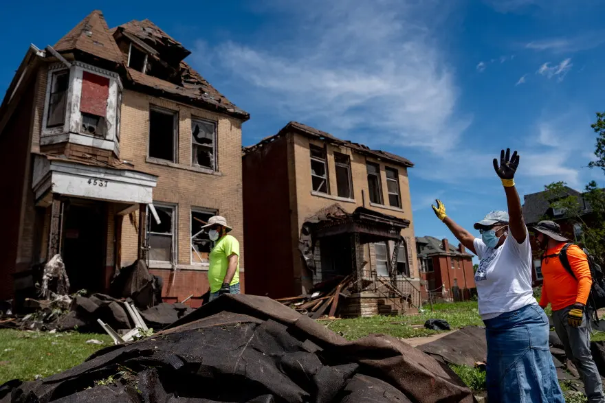 Debra El, of downtown St. Louis, rejoices after volunteers are able to get roof lining off of the road on Saturday, May 17, 2025, in north St. Louis. An EF-3 tornado ripped through the city on Friday afternoon, killing at least 5 and damaging thousands of homes.