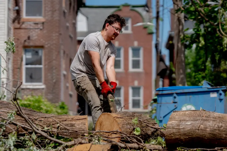 Joey Meinert, 32, of St. Louis’ Carondolet neighborhood, helps cut up wood from fallen trees on Saturday, May 17, 2025, in north St. Louis. An EF-3 tornado ripped through the city on Friday afternoon, killing at least 5 and damaging thousands of homes.