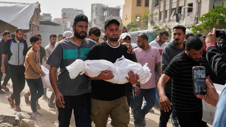 Saleh Zenati, carries the body of his infant nephew Khalid Zenati killed in an Israeli army airstrike, during his funeral in Khan Younis, Gaza Strip, Sunday, May 18, 2025. (AP Photo/Abdel Kareem Hana)