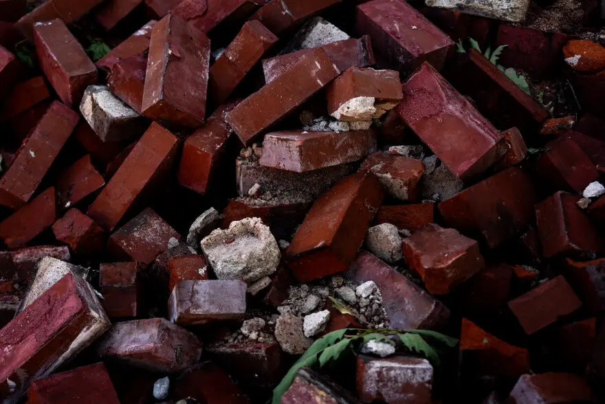 A pile of red bricks sit in a pile near a crumbling home after a tornado ripped through north St. Louis the evening before on Saturday, May 17, 2025. At least 5 were killed and thousands of homes were damaged.