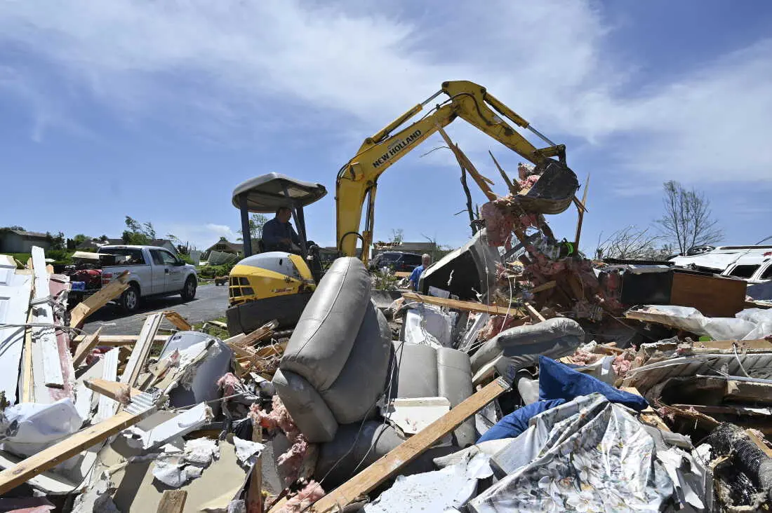 A man uses a back hoe to move debris into a pile following severe storms in London, Ky., on Saturday.