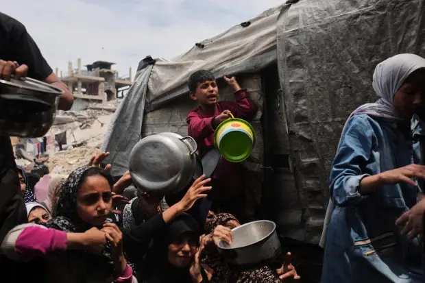 Palestinians struggle to get donated food at a community kitchen...