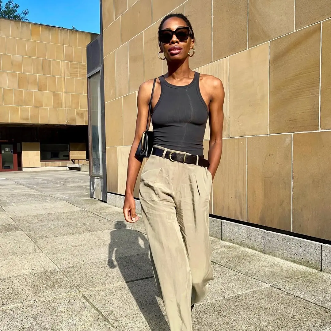 woman wearing cool black tank top and tan trousers